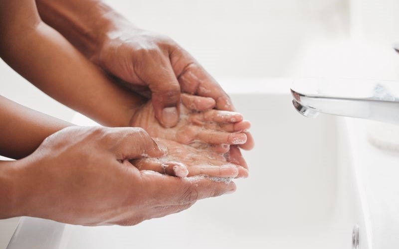 An adult washing a child's hands.