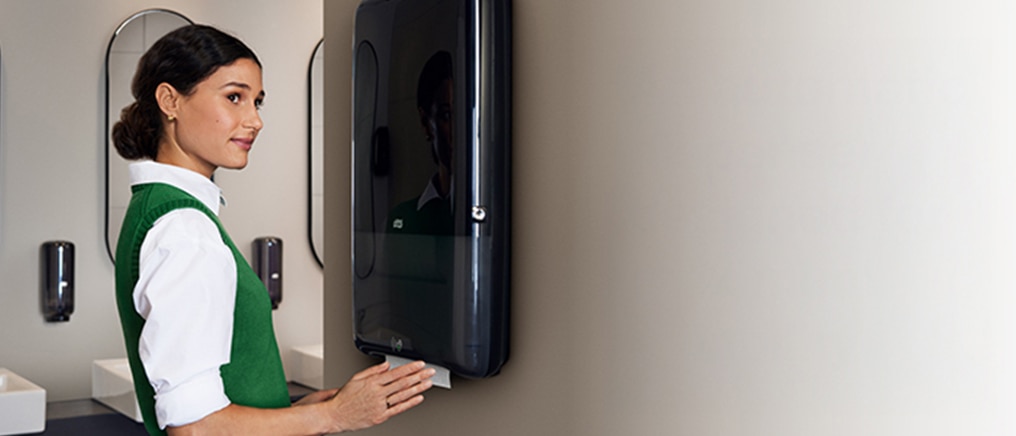 Person using a wall-mounted black hand towel dispenser in a modern restroom. New Tork PeakServe Automatic makes it easier than ever to ensure a great restroom experience   </h1> <p><span style=