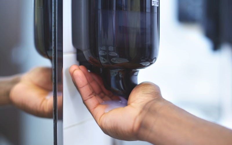 Someone using a black soap dispenser