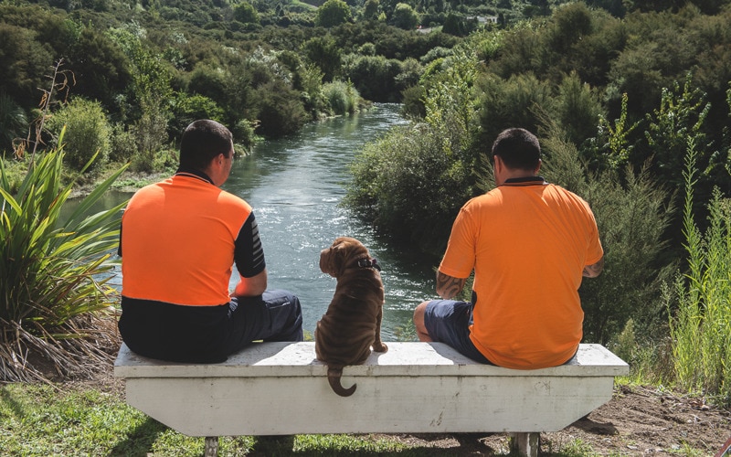 Two workers sitting on a bench looking out at the Tarrawera River.