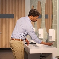 Employee using a soap dispenser at a washroom sink. Employee using a soap dispenser at a washroom sink.