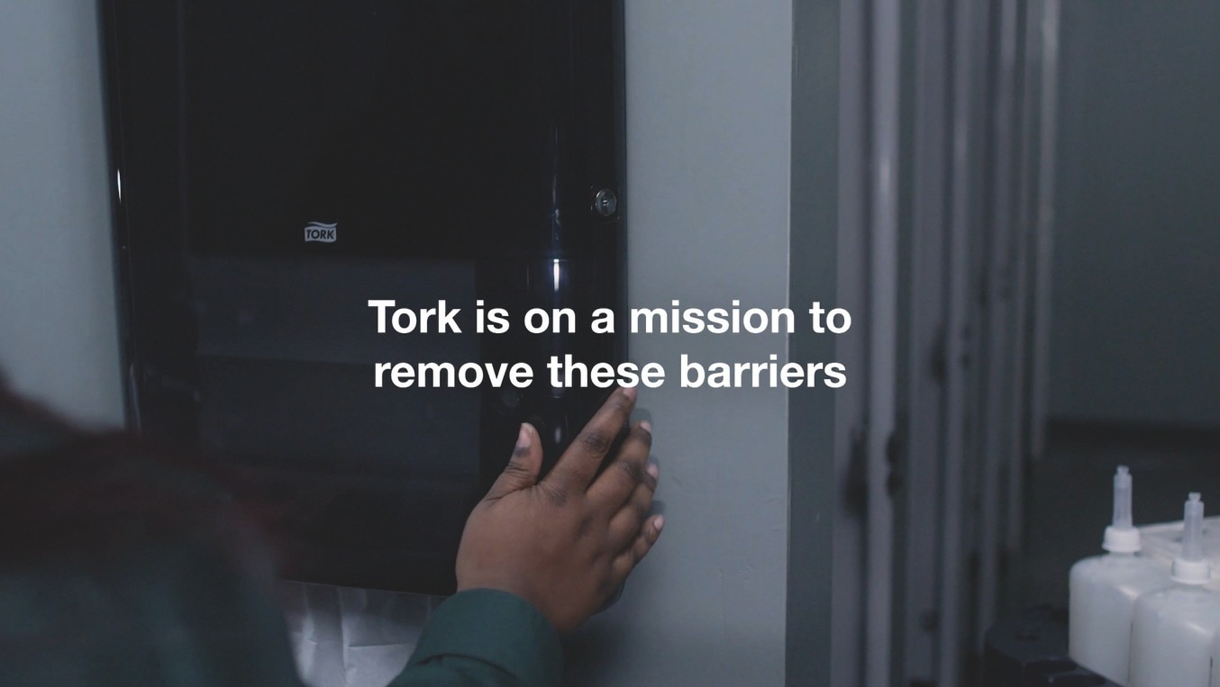 someone closing a Tork PeakServe dispenser with the caption - Tork is on a mission to remove these barriers