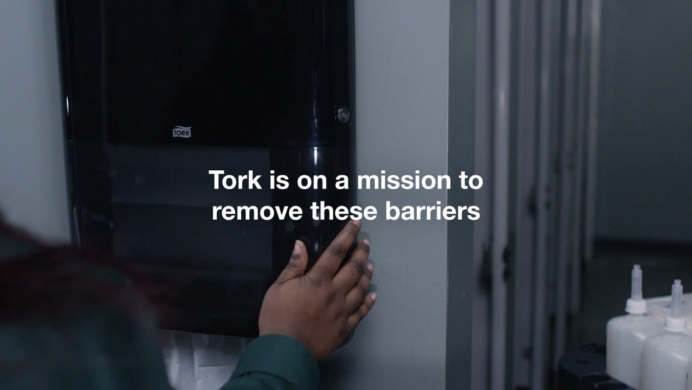 someone closing a Tork PeakServe dispenser with the caption - Tork is on a mission to remove these barriers