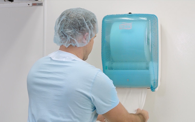 Worker taking paper from the Tork Washstation Dispenser Worker taking paper from the Tork Washstation Dispenser