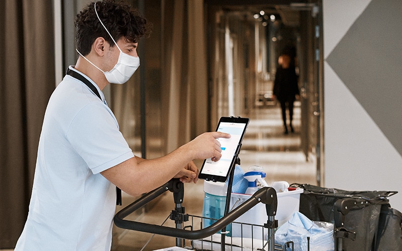 Afbeelding van een schoonmaakmedewerker die Tork Vision Schoonmaken gebruikt op een op een trolley bevestigde tablet