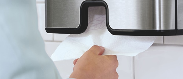 Hand, die ein Papierhandtuch aus einem Spender zieht
