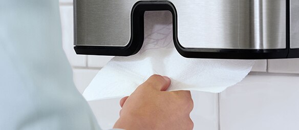 Hand, die ein Papierhandtuch aus einem Spender zieht Hand, die ein Papierhandtuch aus einem Spender zieht