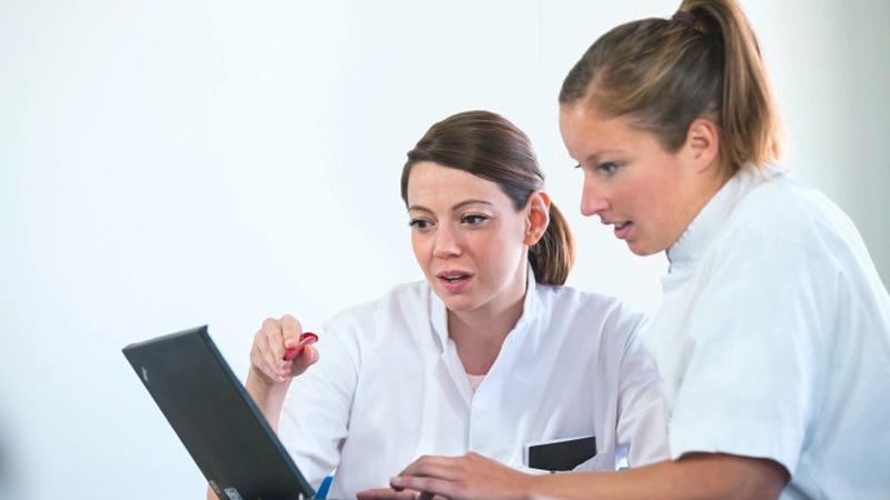 Two healthcare workers using a desktop computer
