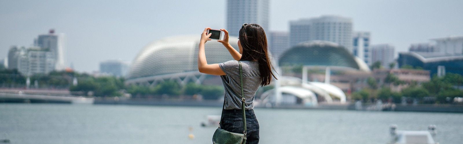 Kobieta fotografuje iPhonem panoramę miasta.