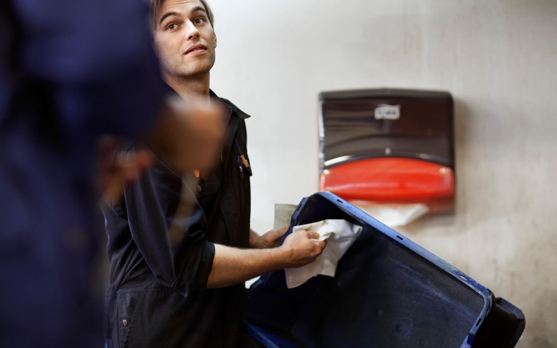 Ένας άντρας τραβάει ένα διπλωμένο πανί καθαρισμού από μια επιτοίχια συσκευή Tork 