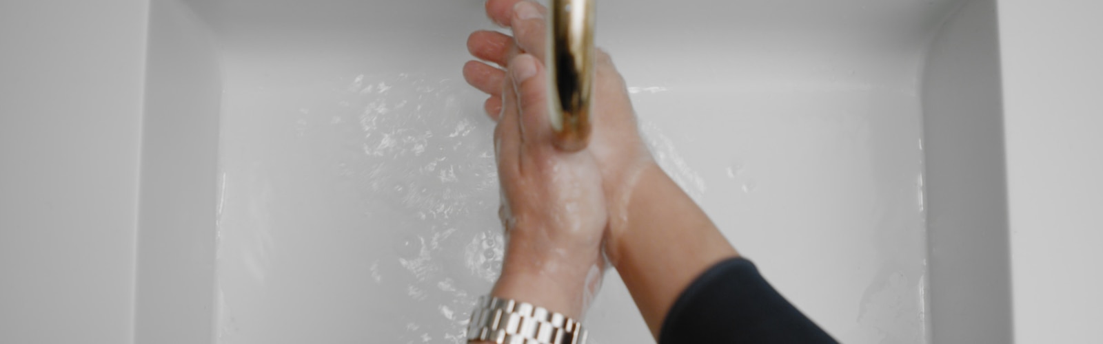 Två händer under rinnande vatten från en kran