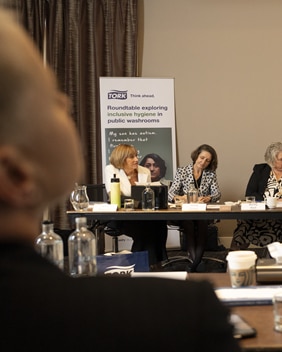 A group of people is participating in a roundtable discussion while seated at a conference table.