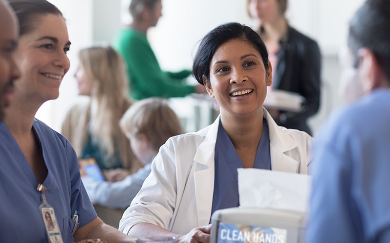 Doctors and nurses talking and laughing, sitting around a table in a canteen