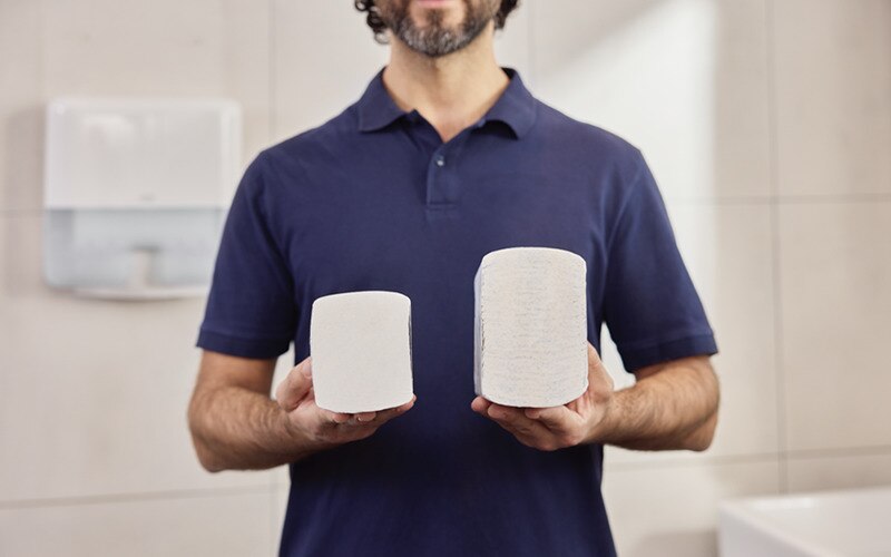 a man holding two piles of paper towels in each hand, one pile is lower than the other one