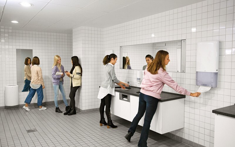 Kvinnor i toalettutrymmen som tvättar och torkar händerna