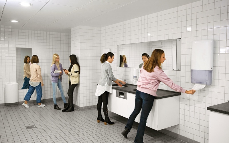 Women in washroom washing and drying hands