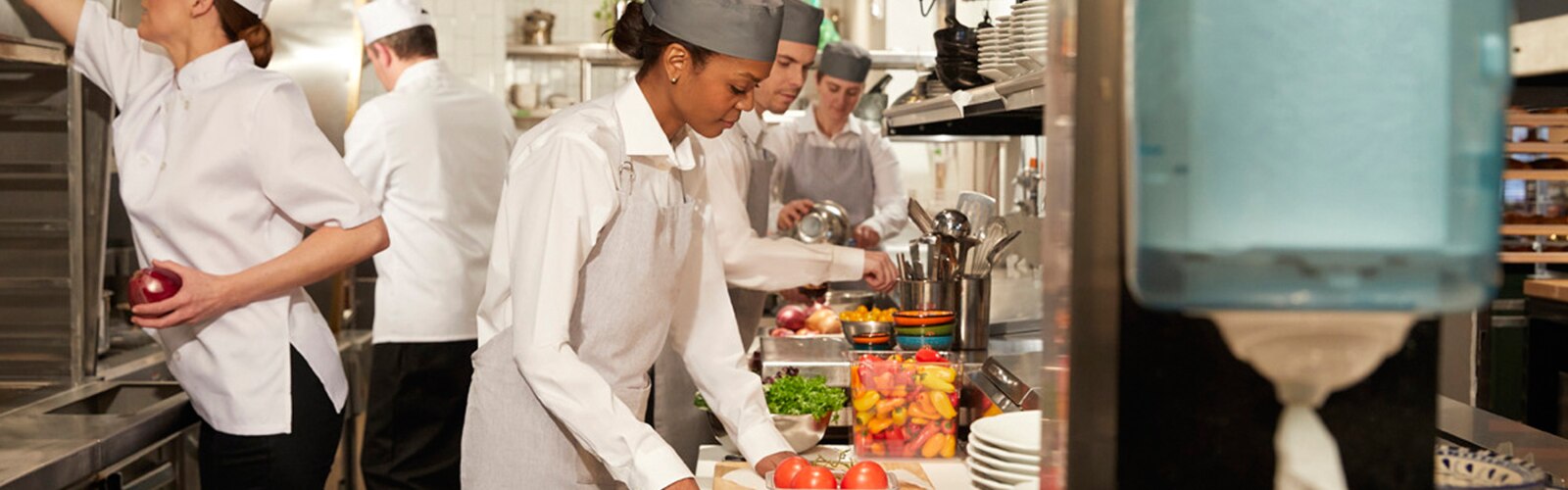 Mulheres e homens na cozinha de um restaurante a preparar refeições
