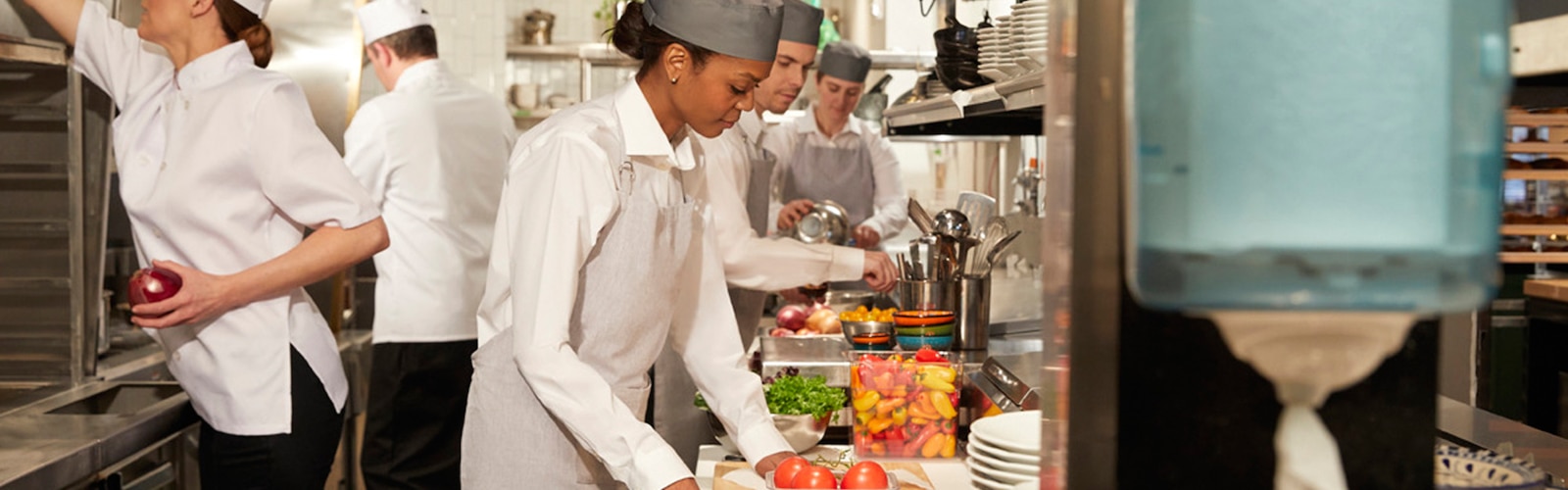 Žene i muškarci u restoranskoj kuhinji pripremaju obroke